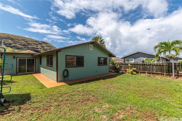 rear view of house with fence and a lawn