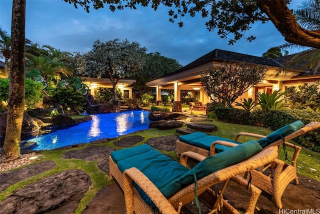 pool at dusk with pool water feature and a patio area