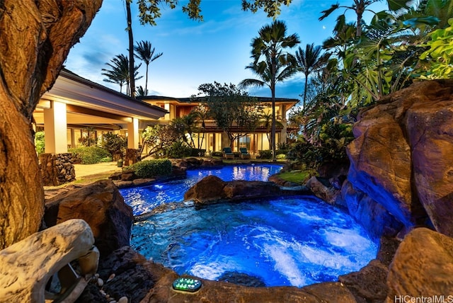 pool at dusk with a patio and a jacuzzi