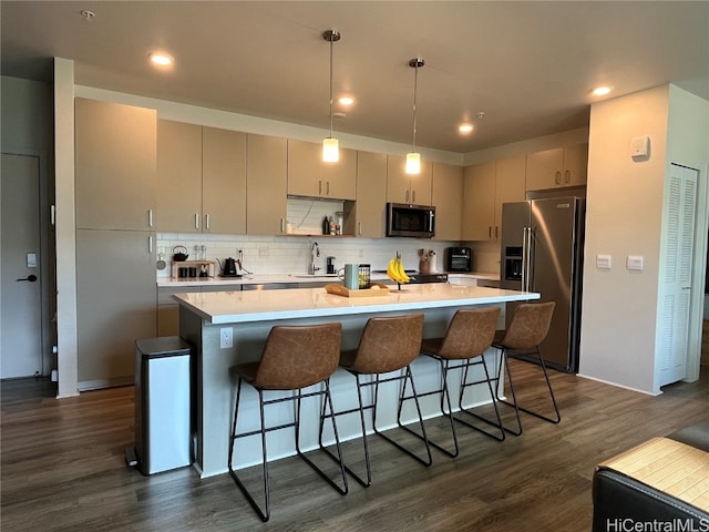 kitchen with dark wood-type flooring, hanging light fixtures, stainless steel appliances, sink, and a center island