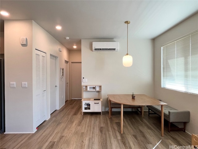 dining space with a wall mounted AC and hardwood / wood-style floors