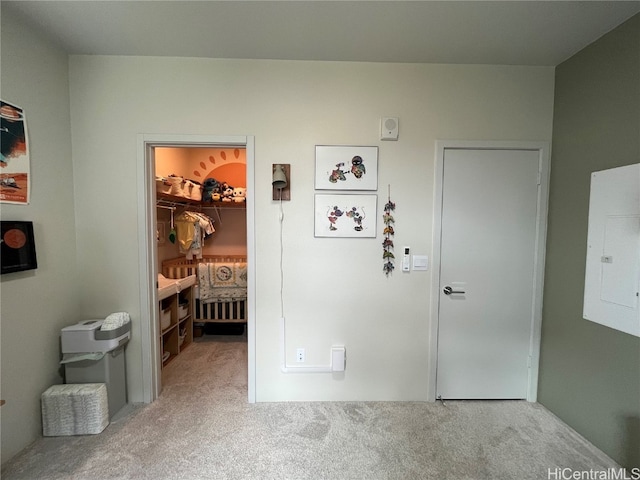 bedroom with electric panel, a walk in closet, a closet, and light colored carpet