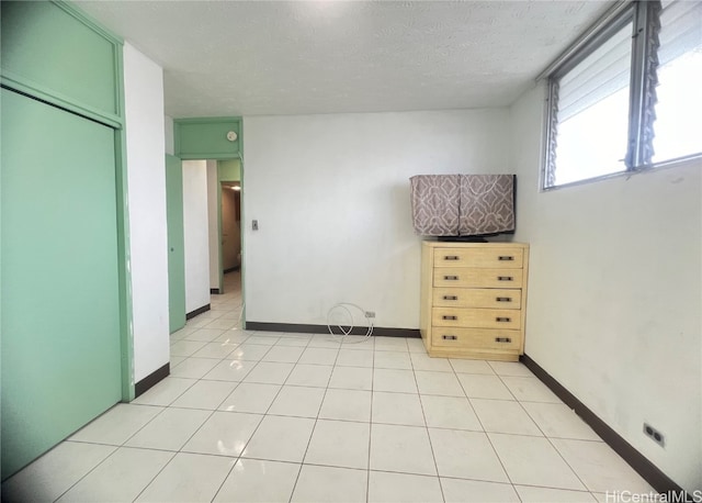 unfurnished bedroom with a closet, a textured ceiling, and light tile patterned floors