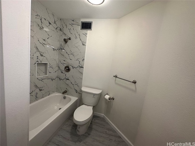 bathroom with toilet, tiled shower / bath combo, and wood-type flooring