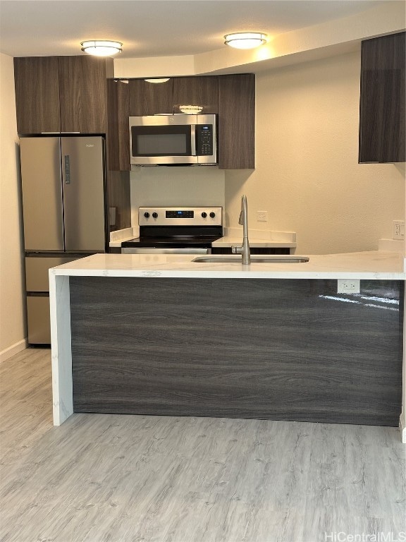 kitchen with sink, light hardwood / wood-style flooring, dark brown cabinets, and stainless steel appliances