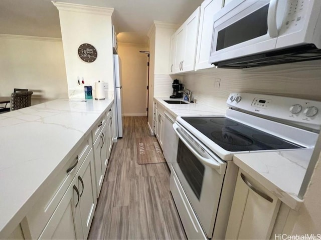 kitchen featuring sink, white cabinets, light stone counters, crown molding, and white appliances