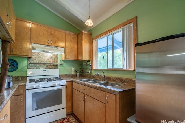 kitchen with pendant lighting, lofted ceiling, sink, stainless steel fridge, and gas range gas stove