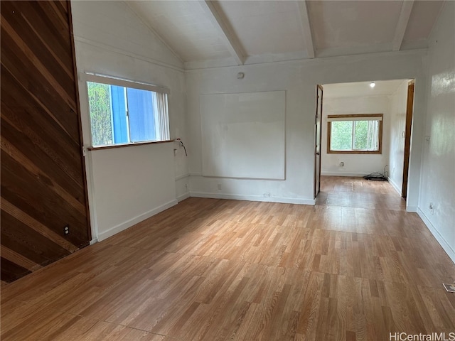 spare room featuring lofted ceiling with beams and light hardwood / wood-style floors