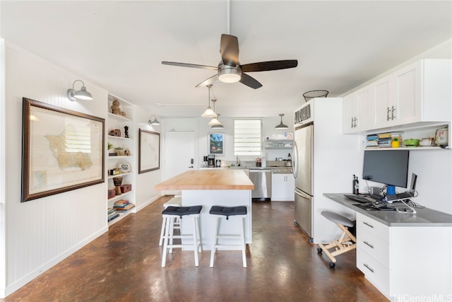 kitchen with butcher block counters, a breakfast bar area, a center island, white cabinets, and appliances with stainless steel finishes