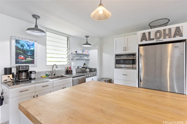 kitchen with appliances with stainless steel finishes, white cabinets, decorative light fixtures, and sink