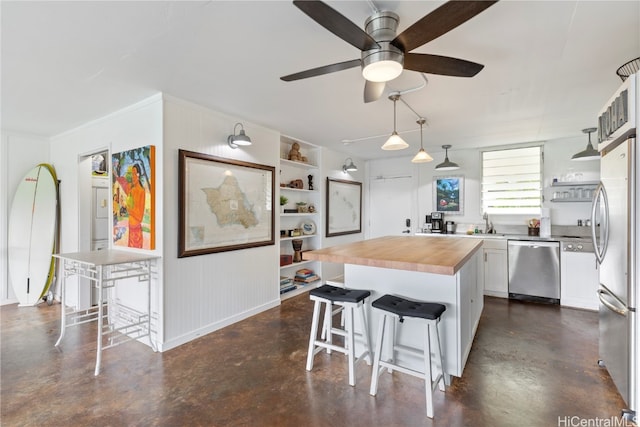 kitchen featuring appliances with stainless steel finishes, white cabinetry, a kitchen bar, and a kitchen island