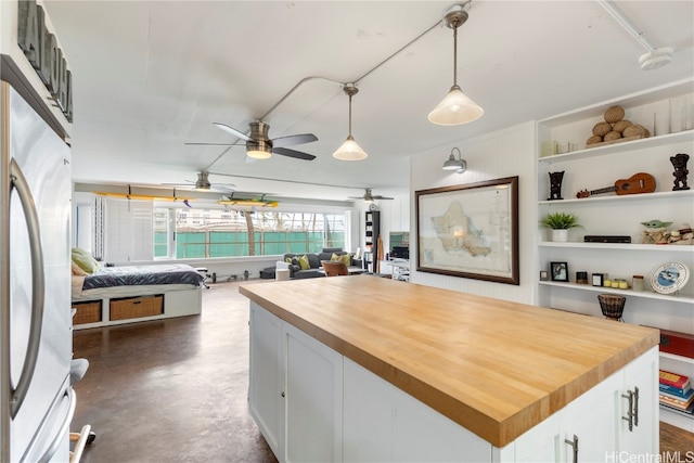 kitchen with a kitchen island, wood counters, decorative light fixtures, white cabinetry, and white fridge