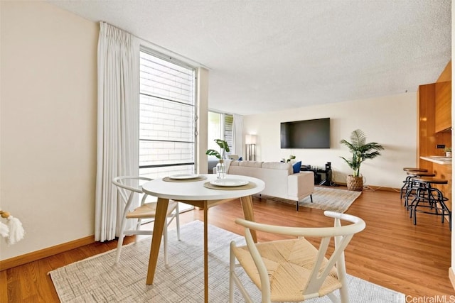 dining space featuring light hardwood / wood-style floors and a textured ceiling