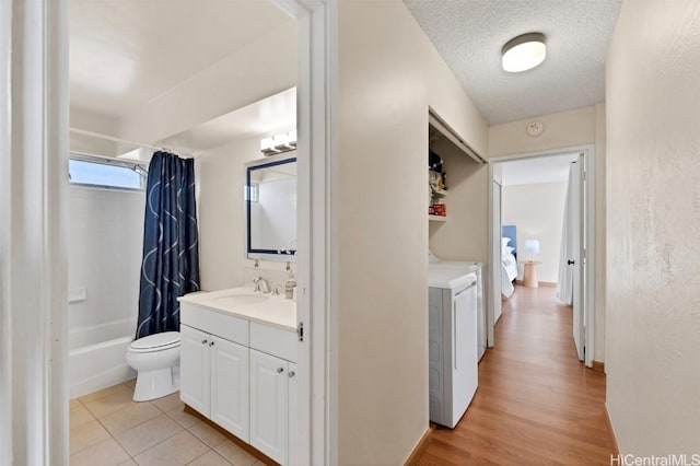 full bathroom featuring toilet, a textured ceiling, vanity, shower / bathtub combination with curtain, and washer and clothes dryer