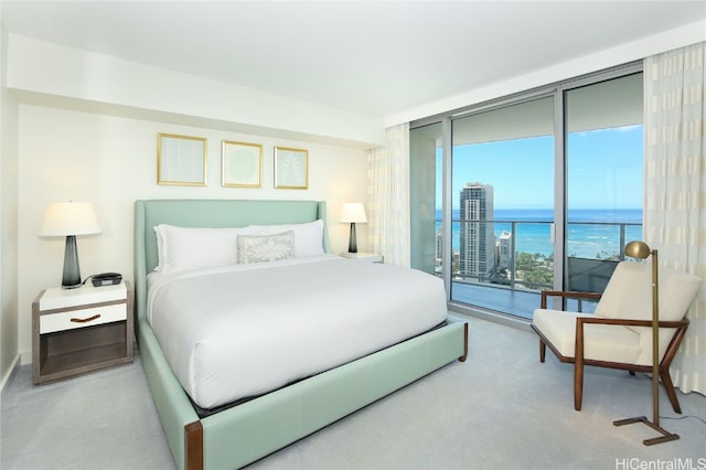 bedroom featuring a water view, light carpet, multiple windows, and access to outside