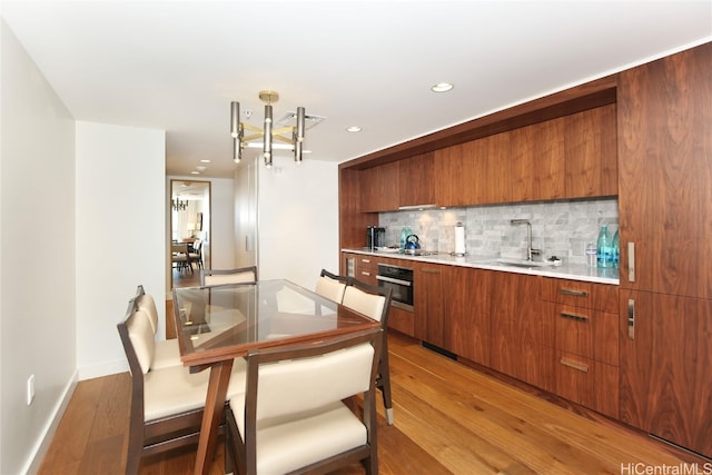 kitchen with oven, hardwood / wood-style floors, sink, and backsplash