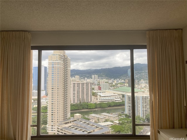 room details with a view of city, a textured ceiling, and a water view