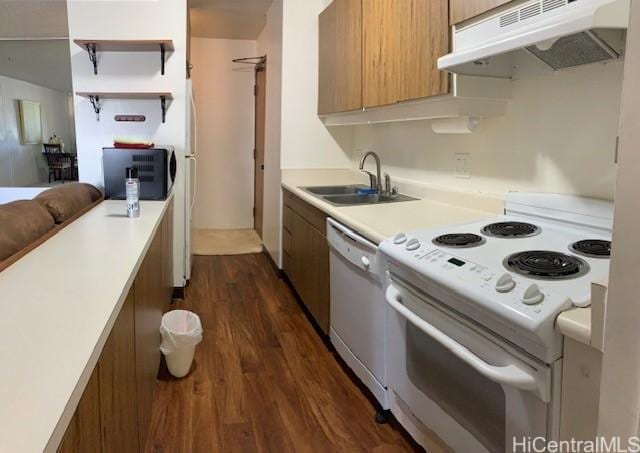 kitchen featuring a sink, under cabinet range hood, white appliances, light countertops, and dark wood-style flooring
