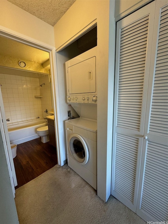 laundry room with stacked washer / dryer, a textured ceiling, laundry area, and carpet