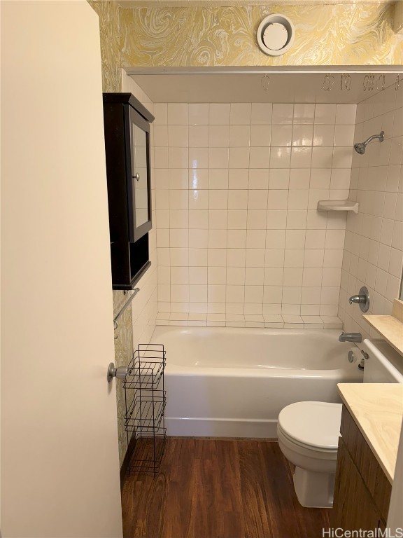 full bathroom with hardwood / wood-style floors, vanity, toilet, and tiled shower / bath