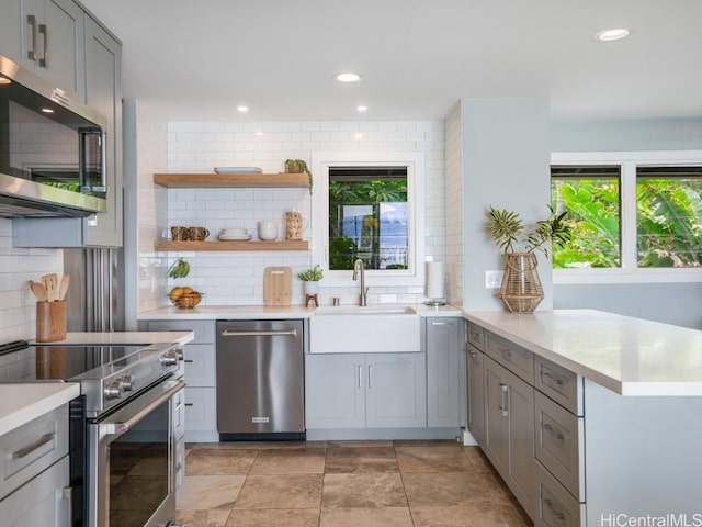 kitchen with sink, backsplash, gray cabinetry, and appliances with stainless steel finishes