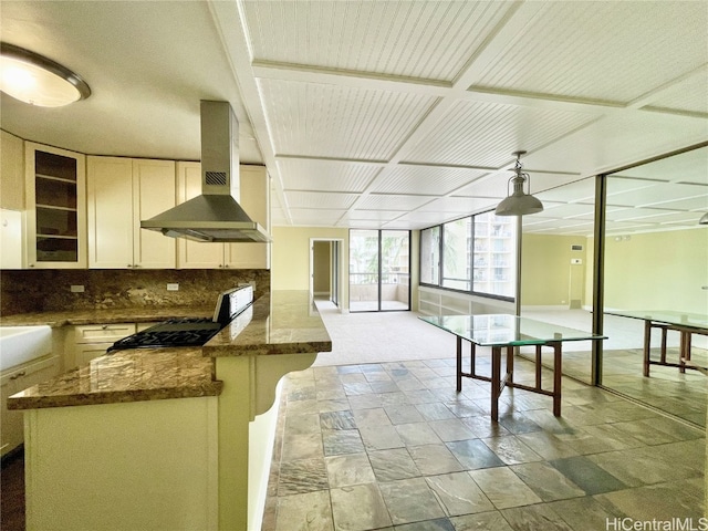 kitchen featuring tasteful backsplash, wall chimney range hood, and dark stone counters