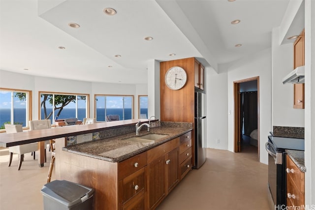 kitchen with concrete floors, under cabinet range hood, freestanding refrigerator, electric range, and a sink