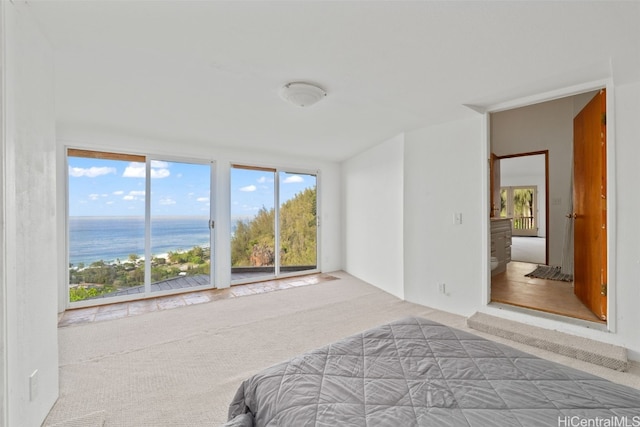 bedroom with access to outside, a water view, and carpet floors