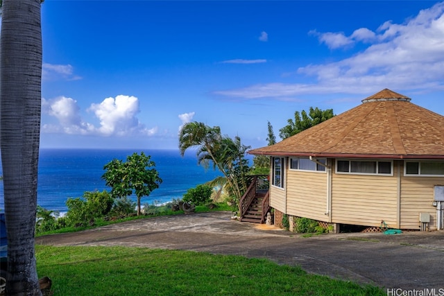 view of home's exterior with a water view and roof with shingles