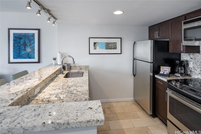 kitchen featuring dark brown cabinetry, sink, stainless steel appliances, light stone counters, and decorative backsplash