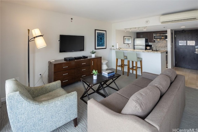 living room with a wall unit AC, sink, and rail lighting