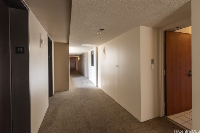 hallway featuring a textured ceiling and light colored carpet