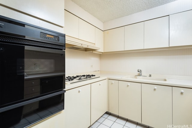 kitchen featuring white gas stovetop, double oven, sink, white cabinetry, and a textured ceiling