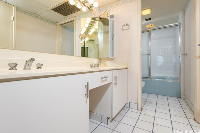 full bathroom with vanity, bath / shower combo with glass door, toilet, and tile patterned flooring