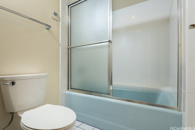 bathroom featuring toilet, bath / shower combo with glass door, and tile patterned flooring