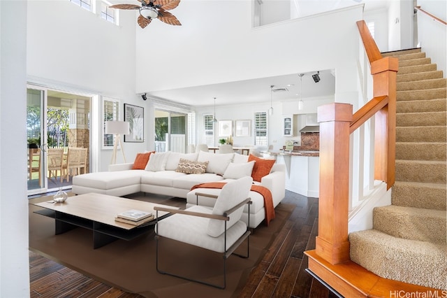 living room featuring dark hardwood / wood-style flooring, a towering ceiling, ceiling fan, and a wealth of natural light