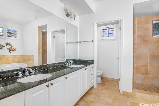 bathroom featuring vanity, toilet, a tile shower, and tile patterned flooring