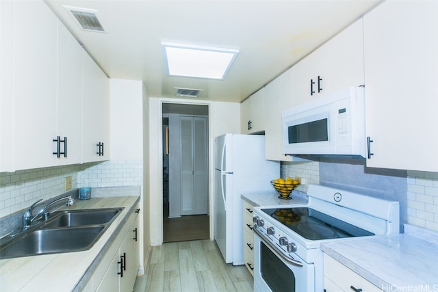 kitchen with white appliances, white cabinets, and sink