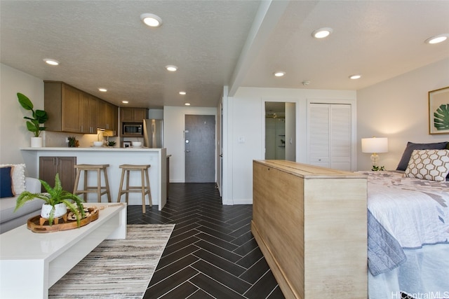 bedroom featuring stainless steel fridge, dark parquet flooring, a textured ceiling, and a closet