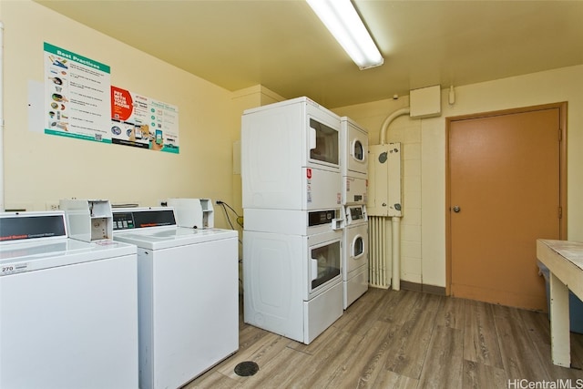 laundry area with light hardwood / wood-style floors, stacked washer / drying machine, and washing machine and clothes dryer