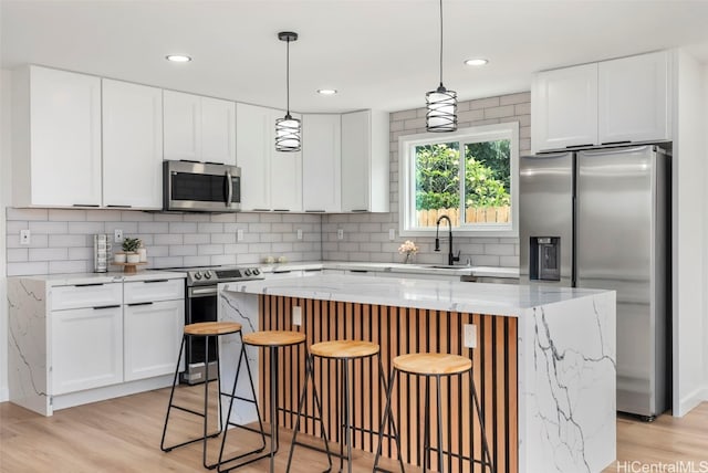 kitchen with a kitchen island, white cabinets, stainless steel appliances, and light hardwood / wood-style floors