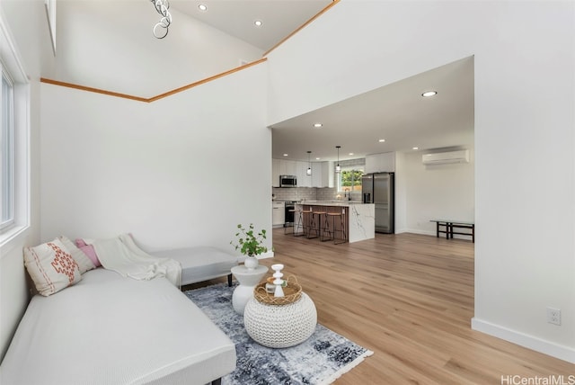 living room featuring light hardwood / wood-style flooring, a wall unit AC, sink, and crown molding