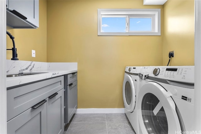 laundry area with sink, washing machine and dryer, light tile patterned floors, and cabinets