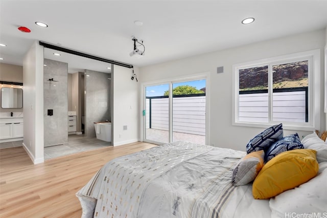 bedroom with connected bathroom, light wood-type flooring, and access to exterior