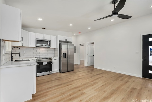 kitchen with sink, white cabinetry, light hardwood / wood-style floors, stainless steel appliances, and decorative backsplash