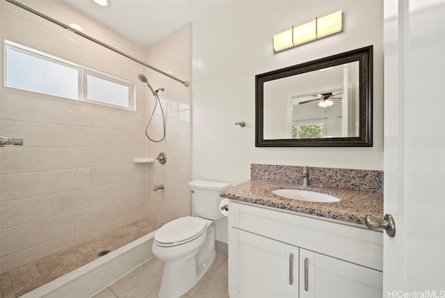 bathroom featuring vanity, a tile shower, toilet, and plenty of natural light