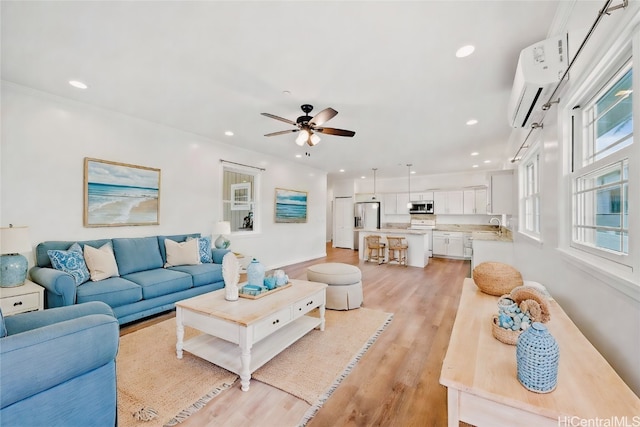 living room featuring an AC wall unit, light wood-type flooring, and ceiling fan