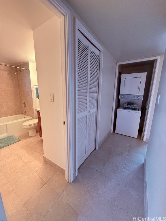 corridor featuring stacked washer / drying machine and light tile patterned floors