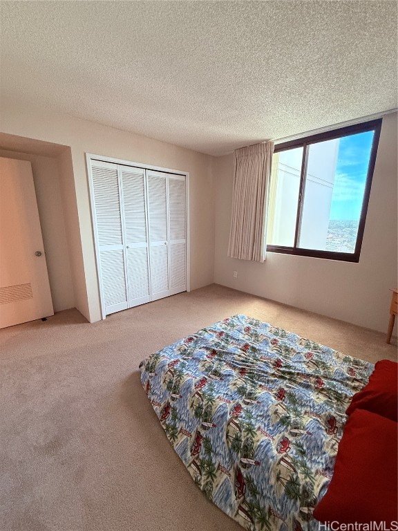 carpeted bedroom with a closet and a textured ceiling