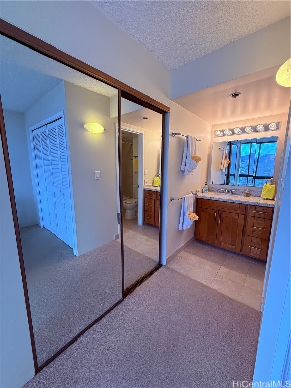 bathroom with vanity, toilet, and a textured ceiling